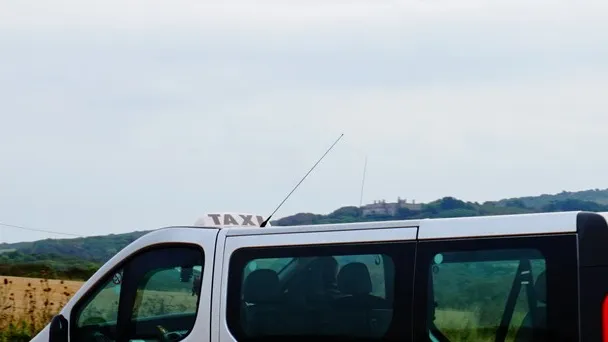 A Door2Door taxi at Brook Chine on the Isle of Wight, with a taxi sign on the roof. Photograph by Ian S, CC BY-SA 2.0.
