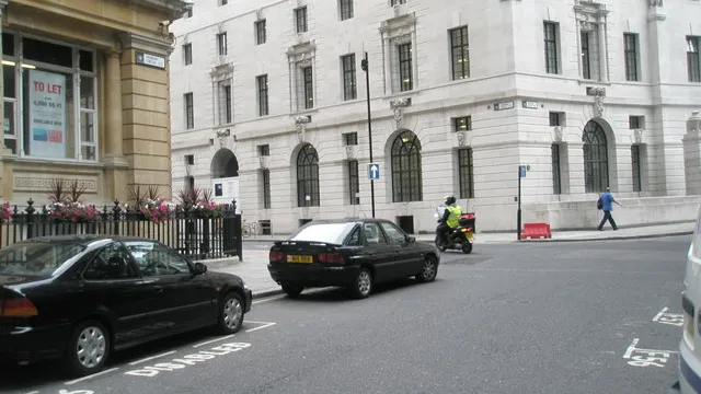 Knowledge student on a scooter with a map board at Finsbury Circus, London