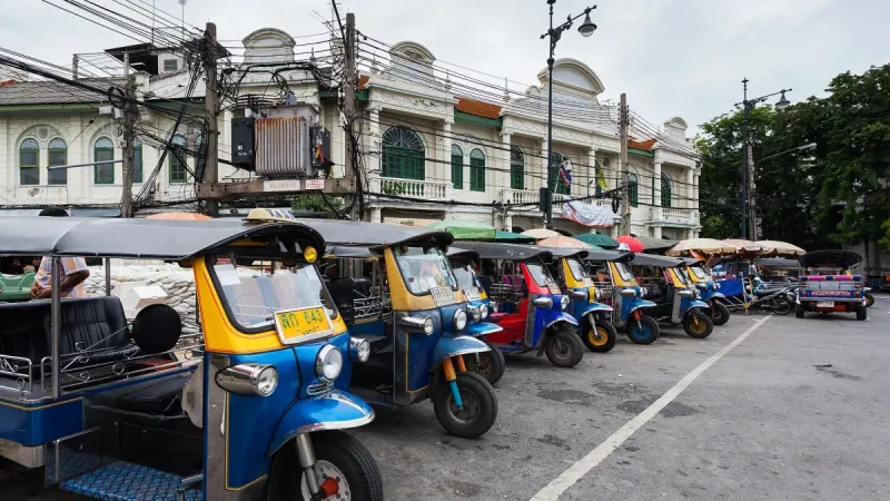 Colourful Bangkok tuk-tuks lined up with illuminated TAXI signs on their roofs